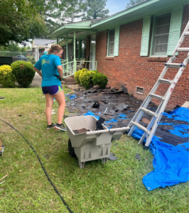 A picture of a Salkehatchie volunteer looking down at debris cleared from a roof.