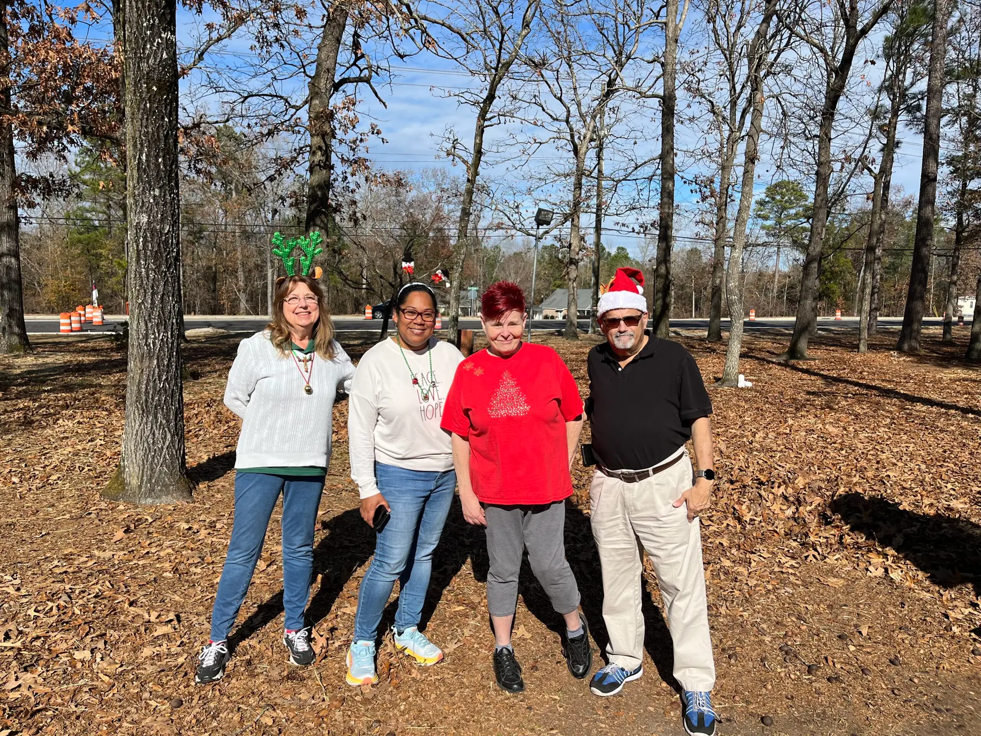 A group of volunteers dressed in christmas-themed shirts and hats pose for a photo