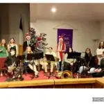A group of youth members poses with instruments during the 2023 Christmas Eve service. Most of the members are dressed up and some have santa hats on.
