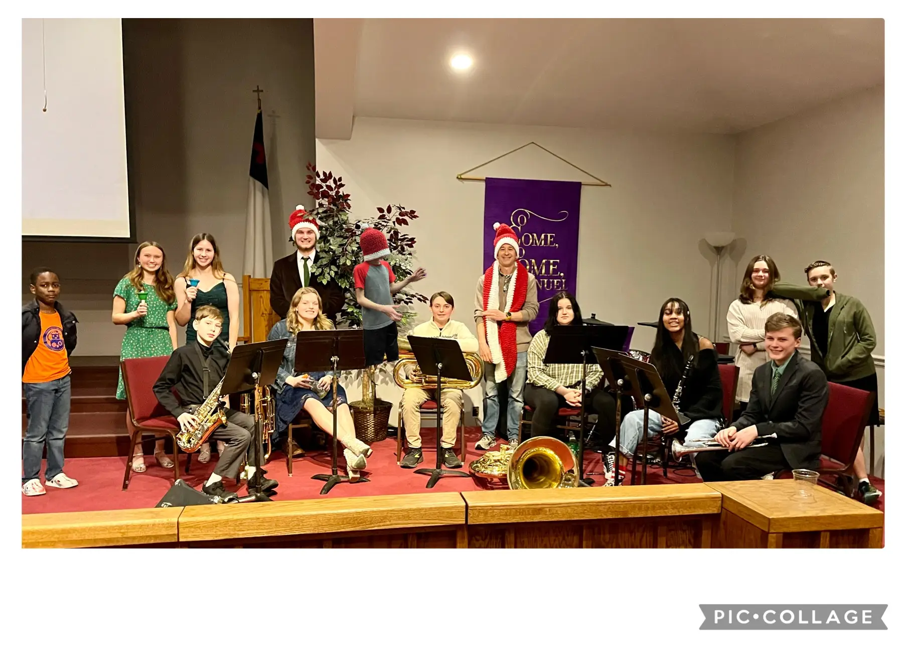 A group of youth members poses with instruments during the 2023 Christmas Eve service. Most of the members are dressed up and some have santa hats on.