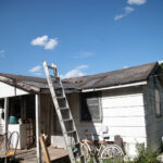 A picture of a 2024 salkehatchie site. There is a ladder leading up to a badly damaged roof with debris on top of it.
