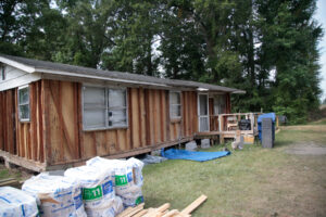 A picture of a Salkehatchie site. It includes a house with the siding torn off to be repaired.