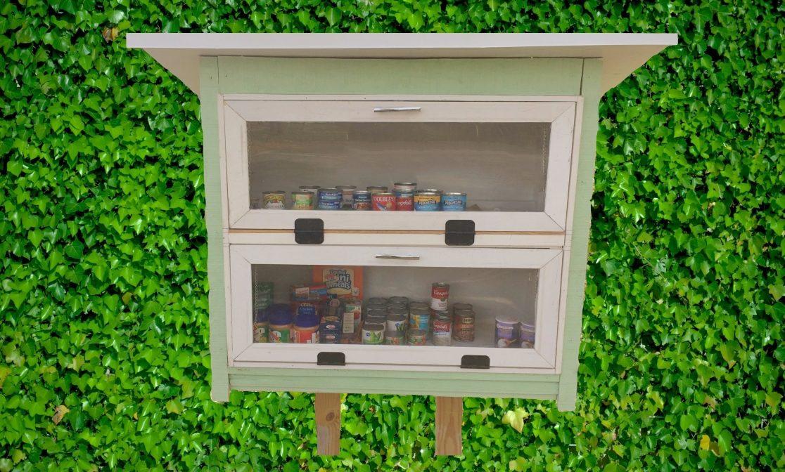 A picture of the blessing box. The doors to the box are closed, but you can see the box is full of canned goods.