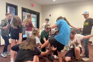 A group of youth members play the human knot game in the education building