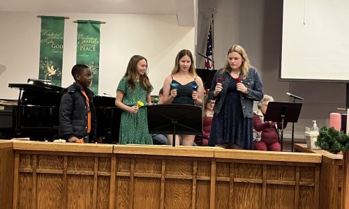 A few youth group members play handbells during the Christmas Eve 2023 service.