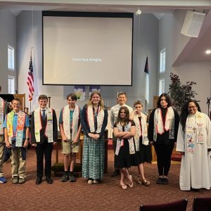 A group of youth confirmands poses for a picture in the church sanctuary